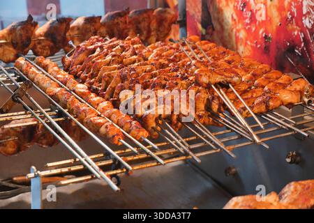 Gegrillte Fleischspieße, die auf einem Metallständer auf dem Markt kochen Stockfoto