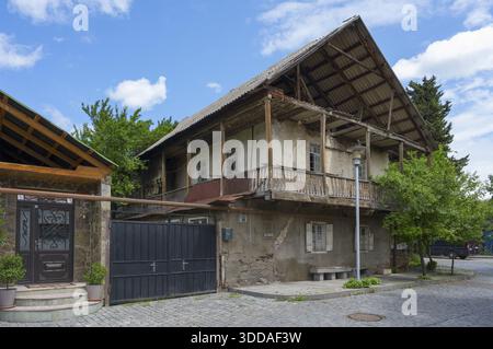 Altes, zweistöckiges Gebäude mit Holzdach und Balkonen umgeben von Bäumen, traditionelles deutsches Wohngebäude, Nikolaistraße 50, Ecke Kirc Stockfoto