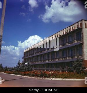 Slawjansk, Ukraine, UdSSR, 1980er Jahre Die Außenansicht des Bogatyr Preventoriums (Kurort), das dem Produktionsverband Khimprom gehört. Das Gebäude verfügt über eine typische sowjetische Resortarchitektur und liegt in einer grünen Zone, wahrscheinlich in der Nähe der Salzseen. Diese Einrichtung bot medizinische Behandlung und Erholung für Chemiearbeiter und deren Familien, was die umfangreichen Sozialleistungen des Unternehmens widerspiegelt. Das Archivbild zeigt die Infrastruktur des Gesundheitswesens und die Lebensqualität der Industriemitarbeiter in der friedlichen Donbass-Stadt. Stockfoto