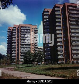 Slawjansk, Ukraine, UdSSR, 1980er Jahre Zwei beeindruckende neue 14-stöckige Wohntürme aus roten Backsteinen erheben sich auf der Svobody Street, die das rasante Wachstum und die Modernisierung der Stadt symbolisieren. Diese hohen Appartementblöcke, die lokal als die „wachsenden Stockwerke von Slawjansk“ bekannt sind, verfügen über geometrische Balkone und stehen vor einem blauen Himmel mit Wolken. Junge Bäume und grünes Gras im Vordergrund weisen auf eine neu entwickelte Nachbarschaft hin. Dieses Archivbild erfasst die Größe des Massenbaus von Wohnhäusern und den architektonischen Stil des friedlichen sowjetischen Donbass. Stockfoto