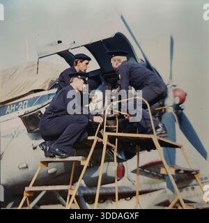 Slawjansk, Ukraine, UdSSR, 1980er Jahre Kadetten der Zivilluftfahrt-Technikschule (SATU) führen während der praktischen Ausbildung Wartungsarbeiten an einem Triebwerk der Antonov an-24 durch. Drei Studenten in dunkelblauen Uniformen, von links nach rechts als S.A. Kochetygov, Yu.L. identifiziert Metik und A.I. Kochevnikov untersuchen den Propellermechanismus von einer gelben Serviceplattform aus. Die offene Verkleidung zeigt interne Komponenten. Dieses Archivbild zeigt die rigorose technische Ausbildung und Vorbereitung von Luftfahrtspezialisten in der friedlichen sowjetischen Stadt. Stockfoto