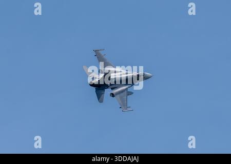 Beja, Portugal - 18. Juni 23: Ein militärischer F-16-Jet fliegt in einem klaren blauen Himmel und zeigt sein schlankes Design und Tarnmuster Stockfoto