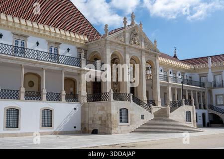 Ein großes architektonisches Gebäude mit kunstvollen Details, mit einer großen Treppe, die zu einem Eingang führt, umgeben von einem Innenhof und blauem Himmel Stockfoto