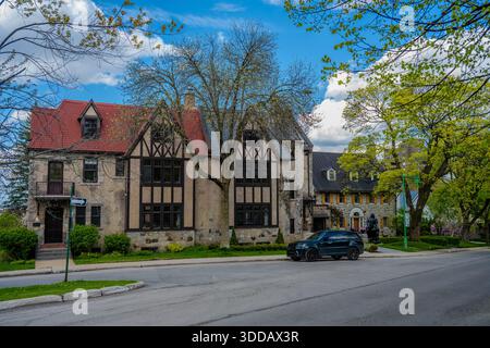 Stein- und Fachwerkhäuser mit roten und dunklen Dächern säumen eine mit Bäumen gefüllte Wohnstraße in Montreal, vor der ein geparkter SUV steht. Montreal, Kanada Stockfoto