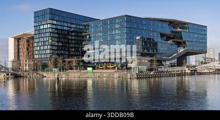 Die moderne Glasarchitektur des Campus des Hauptquartiers Booking.com am Oosterdokseiland in Amsterdam, vom Wasser aus gesehen. Stockfoto