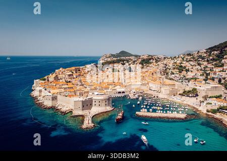 Blick aus der Vogelperspektive auf die Terrakotta-Dächer, die sich hinabstürzen, um das türkisfarbene Wasser und die alten Steinmauern von Dubrovnik, Gespanschaft Dubrovnik-Neretva, Kroatien, zu treffen Stockfoto