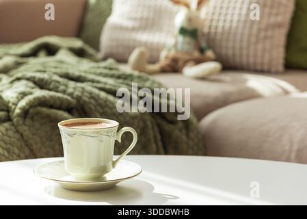 Gemütliches Osterzimmer mit Plüschhasen, Kaffee und Blumen im Sonnenlicht Stockfoto
