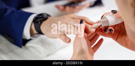 Maniküre-Meister, der mit männlichen Klienten im Schönheitssalon arbeitet. Nagelpflege für Herren. Nahaufnahme Stockfoto