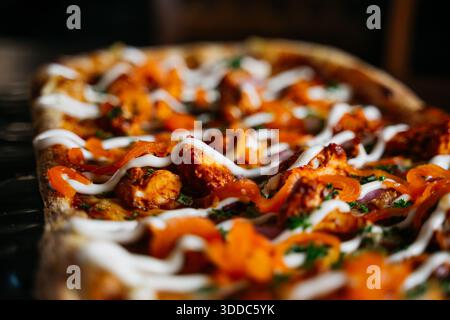 Eine Pizza mit weißer Sauce und roter Paprika. Die Sauce wird auf der Pizza verteilt und die Paprika sind überall verteilt Stockfoto