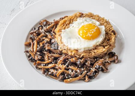 Das gemütliche Reisgericht besteht aus Butterpilzen, Sesamgarnitur und perfekt gekochtem Eigelb Stockfoto