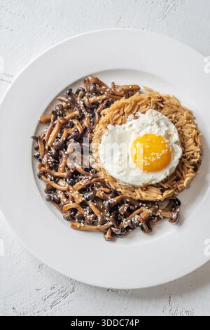 Das gemütliche Reisgericht besteht aus Butterpilzen, Sesamgarnitur und perfekt gekochtem Eigelb Stockfoto