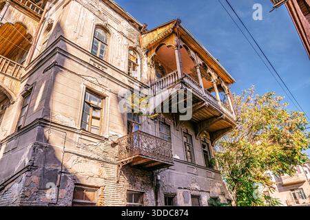 Heruntergekommenes Gebäude mit traditionellen Holzbalkonen und zerbröckelnder Fassade, das die Architektur des alten Tiflis in Georgien widerspiegelt Stockfoto