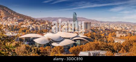 31. Oktober 2025, Tiflis, Georgien: Stadtbild mit der Halle des öffentlichen Dienstes und den Bergen im Herbst, mit moderner Architektur Stockfoto