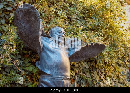 31. Oktober 2025, Tiflis, Georgien: Skulptur eines fröhlichen Mannes mit ausgestreckten Armen, umgeben von üppigem grünem Efeu Stockfoto