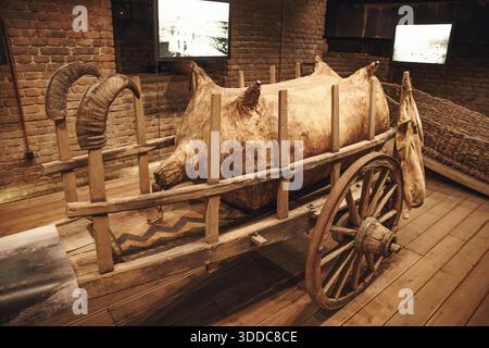 31. Oktober 2025, Tiflis, Georgien: Historischer Holzwagen mit großen Wineskin- und Widderhörnern in einem Museum Stockfoto