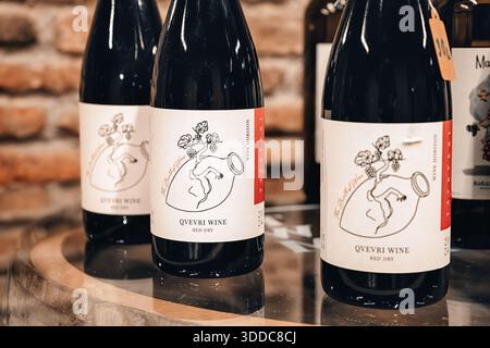 31. Oktober 2025, Tiflis Weinmuseum, Georgien: Qvevri-Weinflaschen mit grafischen Etiketten mit einem traditionellen Tongefäß Stockfoto
