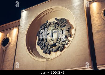 31. Oktober 2025, Tiflis, Georgien: Dekorative Theatermasken an einer Gebäudefassade, beleuchtet bei Nacht mit warmen Lichtern Stockfoto