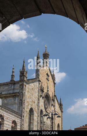 Ein mittelalterlicher Steinkirchenkomplex mit einem hohen Uhrenturm, einer grünen Kupferkuppel und kunstvollen Türmen vor einem hellblauen Himmel. Ausgezeichnet für Bogengewölbe Stockfoto