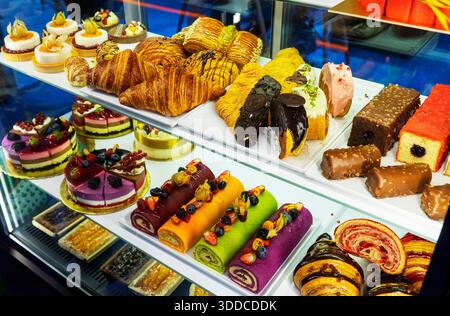 Verschiedene Kuchen mit Sahne und verschiedene Früchte in den Regalen des Ladens Stockfoto