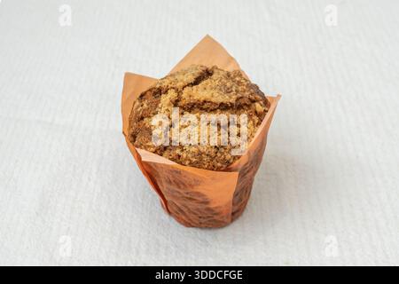 Apfel- und Zimt-Muffin mit karamellisierten Apfelstücken innen, belegt mit Haferbrösel und einer Schaufel Vanilleeis Stockfoto
