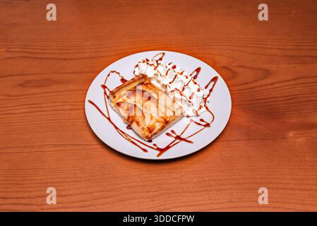 Blätterteiggebäck mit Apfel und getrockneten Preiselbeeren, mit braunem Zucker bestreut vor dem Backen zu einer karamellisierten Kruste, serviert mit Vanillesauce Stockfoto