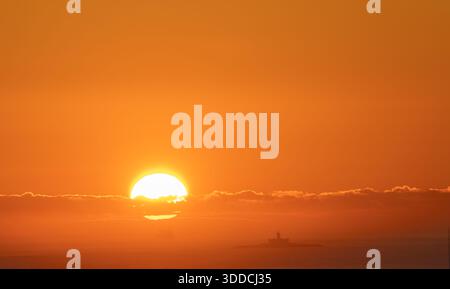 Riesige orangefarbene Sonne geht über Farol do Bugio, Lissabon, Schiff segelt in die Goldene Stunde Stockfoto