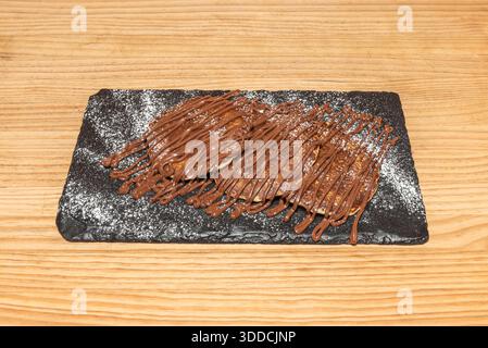 Schokoladenpfannkuchen mit in den Teig eingebetteten Schokoladenchips, garniert mit einer cremigen Schokoladensoße und verziert mit frischen Himbeeren und minzlea Stockfoto