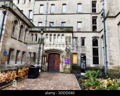 Manchester, Großbritannien - 06. Dezember 2025: Elegante Fassade im Universitätsstil in Manchester mit Bögen, Ziegelpfaden, Efeupflanzen und Herbstfarben. Stockfoto