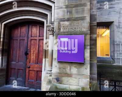 Manchester, Großbritannien - 06. Dezember 2025: Steingebäude in Manchester mit einer bogenförmigen Holztür und einem violetten Charles Beyer Building Schild, urbaner Campus-Atmosphäre. Stockfoto