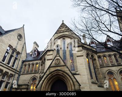 Manchester, Großbritannien - 06. Dezember 2025: Gotische Steinkirche in Manchester, Großbritannien mit beleuchteten Fenstern und einladender Atmosphäre. Stockfoto
