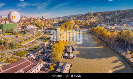 31. Oktober 2025, Tiflis, Georgien: Luftaufnahme von Tiflis im Herbst mit dem Fluss Mtkvari, Brücken, der Altstadt und einem Heißluftballon Stockfoto