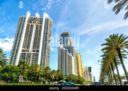 Sunny Isles Beach, USA - 30. April 2024: Florida Road Collins Avenue Street in Miami, Florida mit Autos durch Wohngebäude und Palmen sonnigen Tag Stockfoto