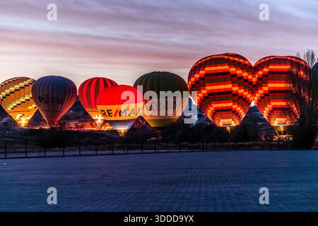 Mehrere Heißluftballons leuchten vor dem Abflug in der Nähe von Göreme in Kappadokien, Türkei, im Morgengrauen. Kommerzielle Ballonflüge über Kappadokien reichen bis ins Jahr 1991 zurück, gegründet von der britischen Pilotin Kaili Kidner und ihrem schwedischen Ehemann Lars-Eric Möre; heute betreiben etwa 27 lizenzierte Unternehmen rund 250 Ballons mit bis zu 156 Flügen und 3.000 bis 4.000 Passagieren pro Tag. Stockfoto