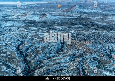 Heißluftballon fliegt über schneebedeckte Landschaft in Göreme, Zentralanatolien, Türkei Stockfoto