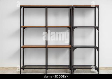 Leeres schwarzes Regal in der Nähe der weißen Wand Stockfoto