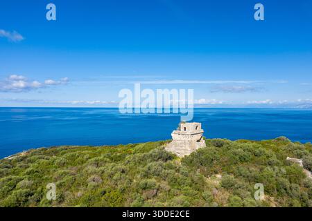 Der historische Steinturm erhebt sich auf der Isola di Cirella, mit ruhigem azurblauem Meer und klarem Himmel, der eine beeindruckende Küstenlandschaft schafft. Helles Sonnenlicht hebt die Texturen der alten Struktur und der umliegenden Natur hervor. Stockfoto