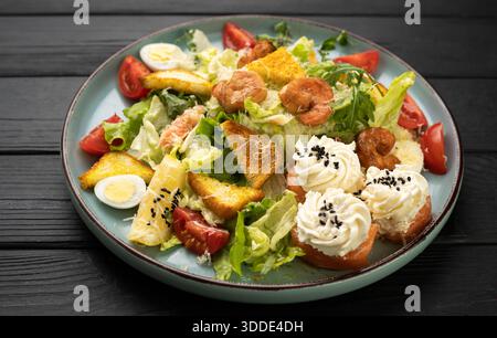 Frischer caesar-Salat mit gebratenen Garnelen, Kirschtomaten, Wachteleiern und knusprigen Croutons auf Teller Stockfoto