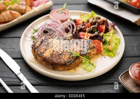 Gegrilltes Schweinefleisch-Steak mit Gemüse auf Holztisch. Grillmenü im Restaurant Stockfoto