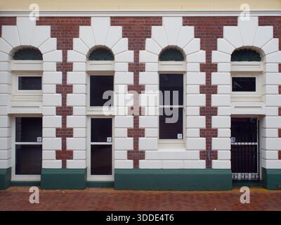 Rote Backsteinfassade mit dekorativen weißen Köpfen und Bogenfenstern Stockfoto