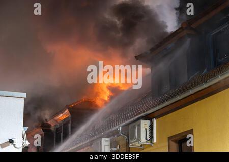 Lieferwagen brennt neben Gebäude Feuer greift auf Dachstuhl über am 31.12.2025 geriet kurz vor 02:00 Uhr ein Lieferwagen in Brand, der direkt neben einem Gebäude mit Wohn- und Geschäftseinheiten in Bickenbach Stand. Die Flammen griffen auf den angrenzenden Dachstuhl über und breiteten sich auf dem Großteil des Dachbodens aus. Da dieser nicht von innen erreichbar war, müssen die Einsatzkräfte die gesamten Dachziegel entfernen, um gezielte Löschmaßnahmen durchführen zu können. Vier Drehleitern sowie ein Mast der Werkfeuerwehr Merck kam zum Einsatz. Winterliche Minusgrade erschwerten die Lösc Stockfoto