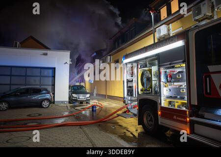 Lieferwagen brennt neben Gebäude Feuer greift auf Dachstuhl über am 31.12.2025 geriet kurz vor 02:00 Uhr ein Lieferwagen in Brand, der direkt neben einem Gebäude mit Wohn- und Geschäftseinheiten in Bickenbach Stand. Die Flammen griffen auf den angrenzenden Dachstuhl über und breiteten sich auf dem Großteil des Dachbodens aus. Da dieser nicht von innen erreichbar war, müssen die Einsatzkräfte die gesamten Dachziegel entfernen, um gezielte Löschmaßnahmen durchführen zu können. Vier Drehleitern sowie ein Mast der Werkfeuerwehr Merck kam zum Einsatz. Winterliche Minusgrade erschwerten die Lösc Stockfoto