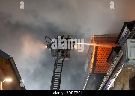 Lieferwagen brennt neben Gebäude Feuer greift auf Dachstuhl über am 31.12.2025 geriet kurz vor 02:00 Uhr ein Lieferwagen in Brand, der direkt neben einem Gebäude mit Wohn- und Geschäftseinheiten in Bickenbach Stand. Die Flammen griffen auf den angrenzenden Dachstuhl über und breiteten sich auf dem Großteil des Dachbodens aus. Da dieser nicht von innen erreichbar war, müssen die Einsatzkräfte die gesamten Dachziegel entfernen, um gezielte Löschmaßnahmen durchführen zu können. Vier Drehleitern sowie ein Mast der Werkfeuerwehr Merck kam zum Einsatz. Winterliche Minusgrade erschwerten die Lösc Stockfoto