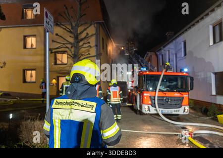 Lieferwagen brennt neben Gebäude Feuer greift auf Dachstuhl über am 31.12.2025 geriet kurz vor 02:00 Uhr ein Lieferwagen in Brand, der direkt neben einem Gebäude mit Wohn- und Geschäftseinheiten in Bickenbach Stand. Die Flammen griffen auf den angrenzenden Dachstuhl über und breiteten sich auf dem Großteil des Dachbodens aus. Da dieser nicht von innen erreichbar war, müssen die Einsatzkräfte die gesamten Dachziegel entfernen, um gezielte Löschmaßnahmen durchführen zu können. Vier Drehleitern sowie ein Mast der Werkfeuerwehr Merck kam zum Einsatz. Winterliche Minusgrade erschwerten die Lösc Stockfoto