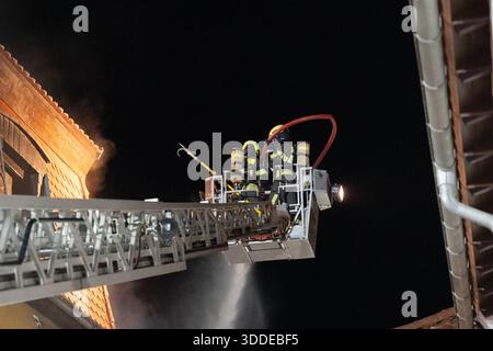 Lieferwagen brennt neben Gebäude Feuer greift auf Dachstuhl über am 31.12.2025 geriet kurz vor 02:00 Uhr ein Lieferwagen in Brand, der direkt neben einem Gebäude mit Wohn- und Geschäftseinheiten in Bickenbach Stand. Die Flammen griffen auf den angrenzenden Dachstuhl über und breiteten sich auf dem Großteil des Dachbodens aus. Da dieser nicht von innen erreichbar war, müssen die Einsatzkräfte die gesamten Dachziegel entfernen, um gezielte Löschmaßnahmen durchführen zu können. Vier Drehleitern sowie ein Mast der Werkfeuerwehr Merck kam zum Einsatz. Winterliche Minusgrade erschwerten die Lösc Stockfoto