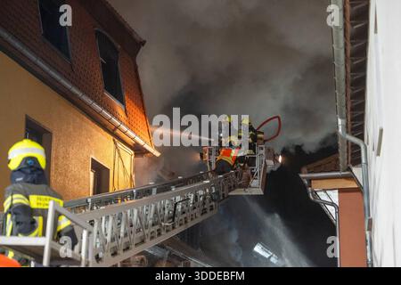 Lieferwagen brennt neben Gebäude Feuer greift auf Dachstuhl über am 31.12.2025 geriet kurz vor 02:00 Uhr ein Lieferwagen in Brand, der direkt neben einem Gebäude mit Wohn- und Geschäftseinheiten in Bickenbach Stand. Die Flammen griffen auf den angrenzenden Dachstuhl über und breiteten sich auf dem Großteil des Dachbodens aus. Da dieser nicht von innen erreichbar war, müssen die Einsatzkräfte die gesamten Dachziegel entfernen, um gezielte Löschmaßnahmen durchführen zu können. Vier Drehleitern sowie ein Mast der Werkfeuerwehr Merck kam zum Einsatz. Winterliche Minusgrade erschwerten die Lösc Stockfoto