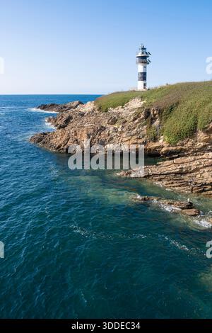 Moderner schwarz-weißer Leuchtturm auf einer felsigen Klippe am tiefblauen Meer unter klarem Himmel, Isla de Pancha, Ribadeo, Galicien, Spanien, vertikal Stockfoto