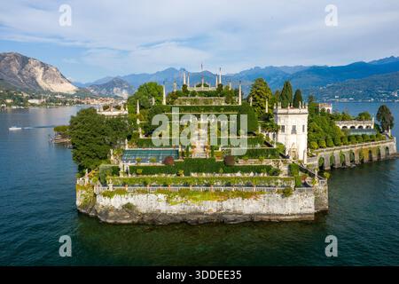 Kunstvolle barocke Gartenterrassen und ein großer Palast ragen über die Küste der Isola Bella, umgeben vom blauen Wasser des Lago Maggiore. Die Szene bietet gepflegtes Grün, kunstvolle Statuen und eine dramatische Bergkulisse in Norditalien. Stockfoto