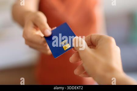 Nahaufnahme einer jungen Frau, die blaue Kreditkarte zur Hand gibt Stockfoto
