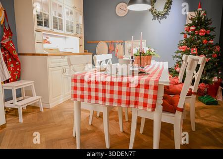Speisesaal mit einem Tisch mit rotem Gingham-Läufer und einem geschmückten weihnachtsbaum. Stockfoto