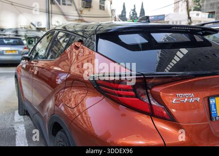Dreiviertelansicht einer zweifarbigen Toyota C-HR Hybrid-Crossover in weiß-Schwarz, geparkt auf einem Stadtgrundstück, Ramat Gan, Israel, 24. Dezember 2025 Stockfoto